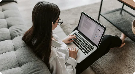 A developer working on a laptop from a sofa