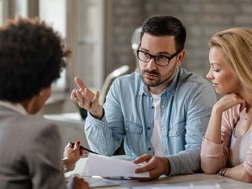 Three people talking through project requirements over printed documents